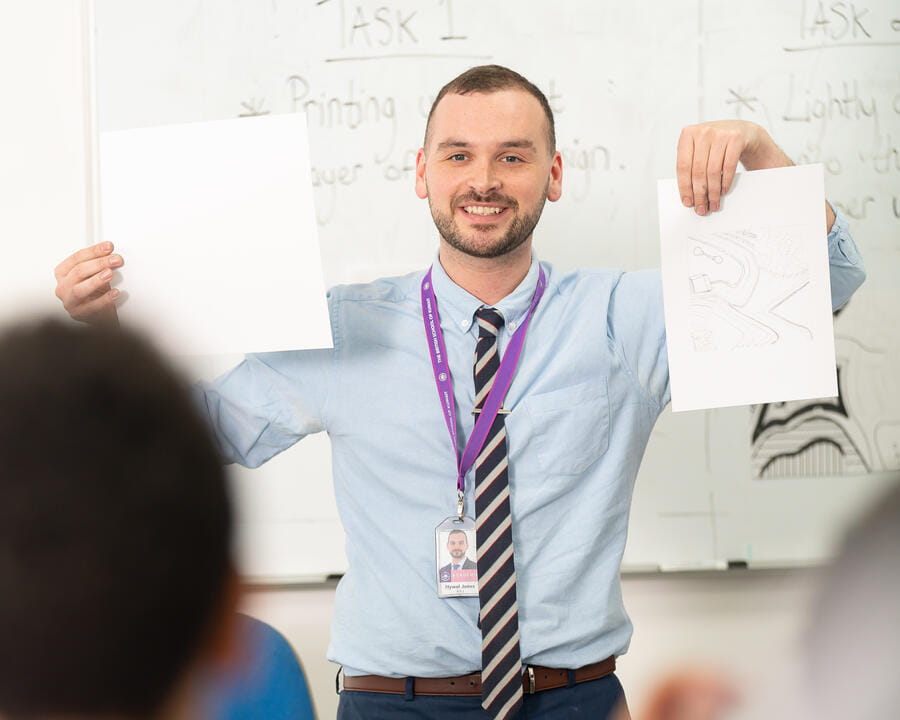 A teacher holding up two sheets of paper