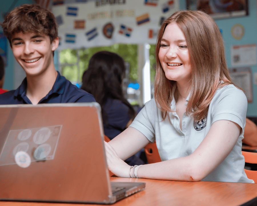 students-smiling-at-computer-in-classroom