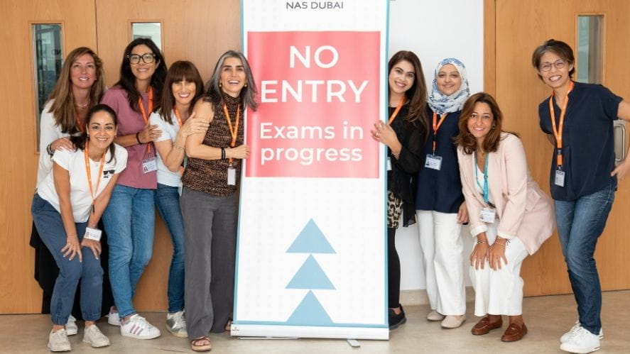 Parents from the NAS Dubai community volunteering as exam invigilators stand beside a “No Entry – Exams in Progress” sign, supporting a focused and well-managed assessment environment.