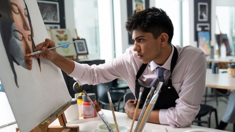 Sixth form art student in art studio at nas dubai wearing nas dubai branded apron